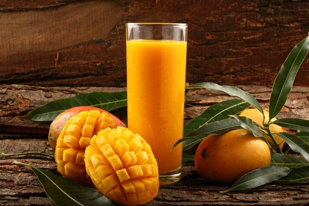 A glass of mango juice with ripe cubed cut mangoes