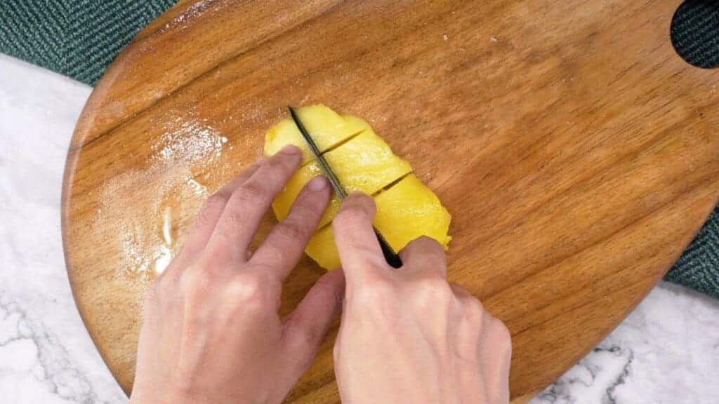 A person cutting mango on a cutting board