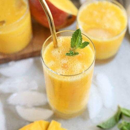 A top view of mango juice in a glass with mint garnish