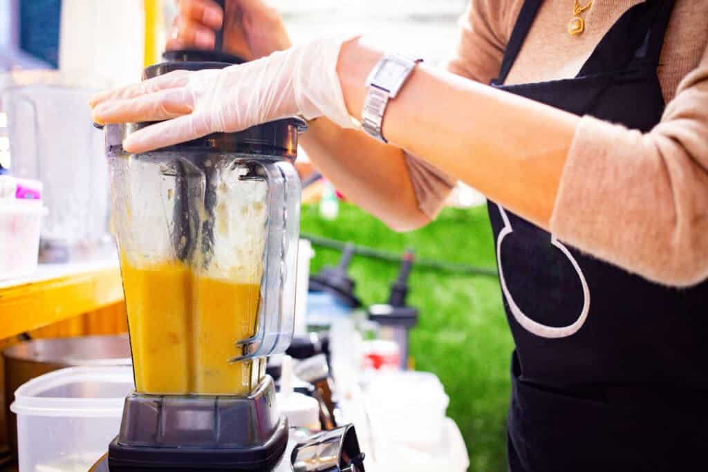 A view of a woman blending mango juice in blender