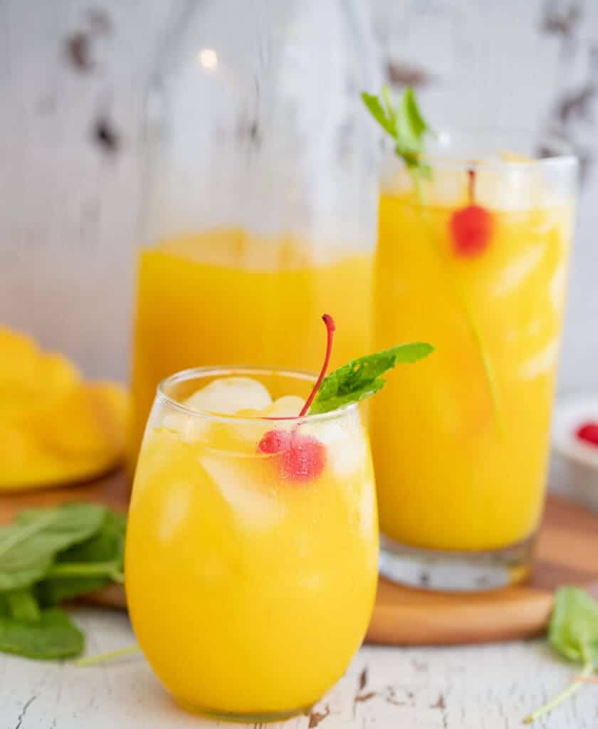 Cold glasses of mango juice with cherry and mint garnish