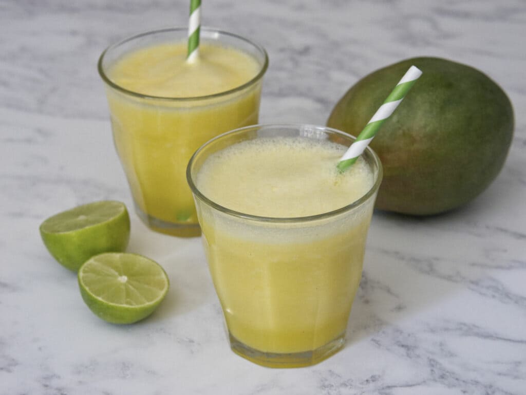 Two glasses of mango juice with lime with a lime cut in half