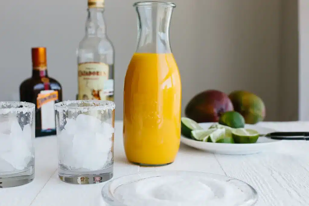 Mango Margarita jar and two glasses filled with crushed ice 