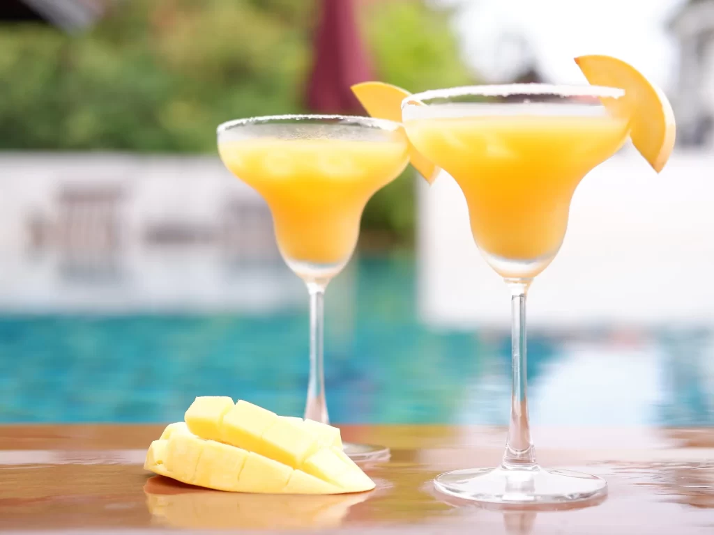 two glasses of mango ginger martini with mango slices on top