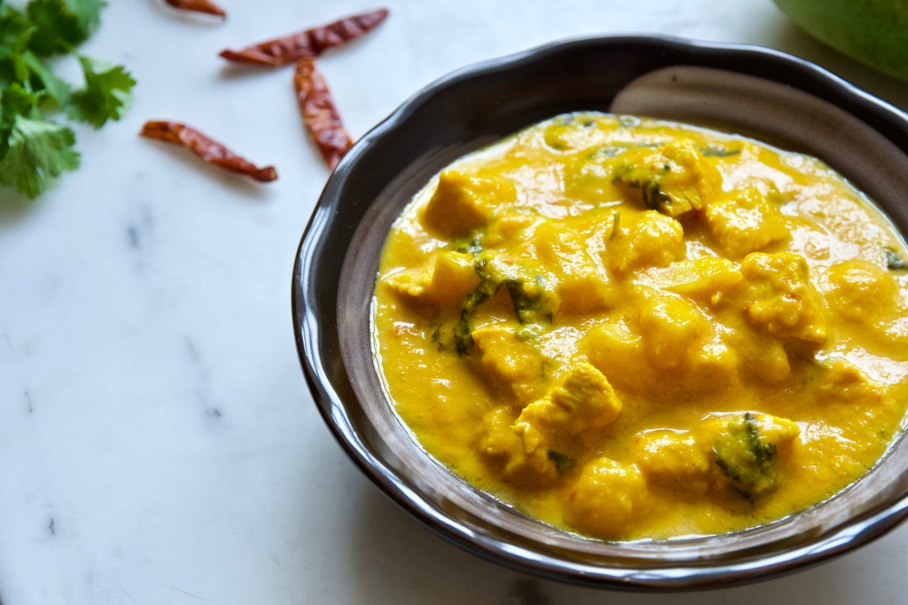 Indian Chicken mango Curry Served In Dark Brown Cup 