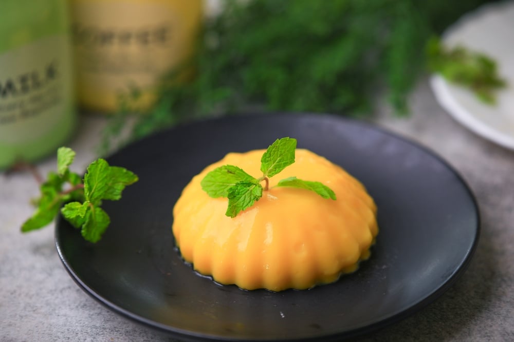 Mango Pudding on a black plate garnished with mint leaves