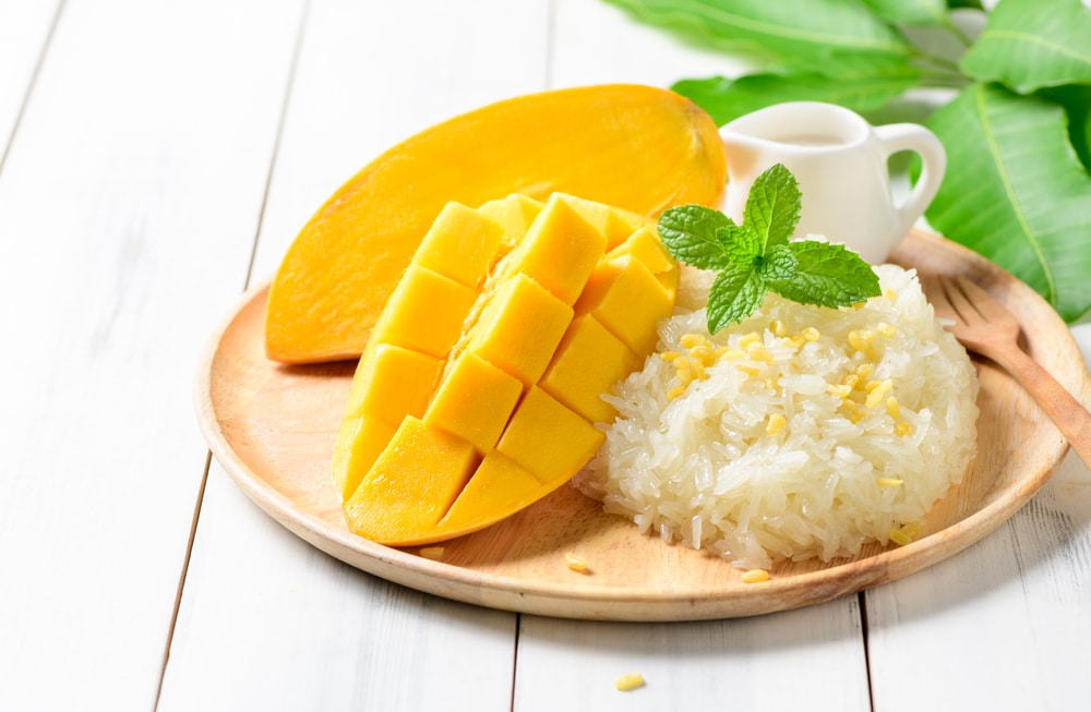 Ripe mango and sticky rice with coconut milk on white wood background