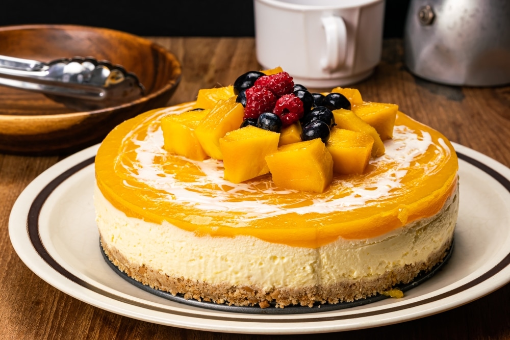 Side View Of Delicious Homemade Mango Cheesecake Garnished With Pieces