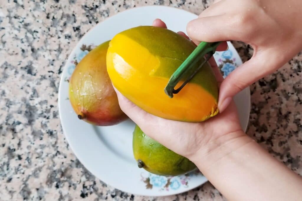 An overview of a mango being peeled