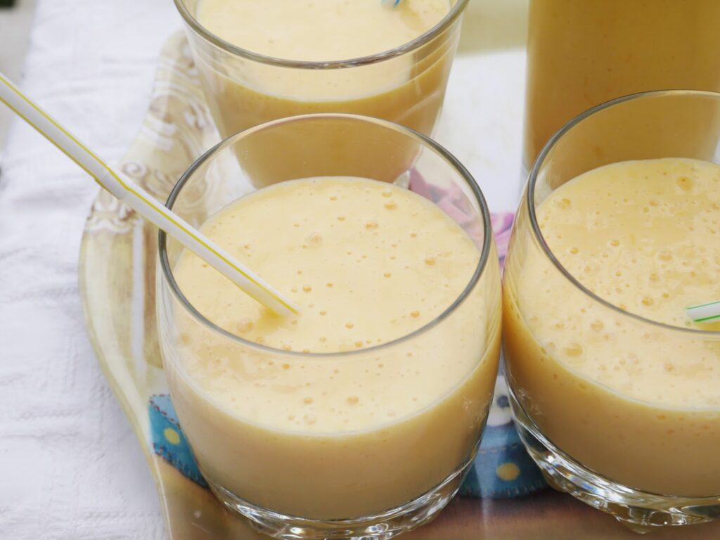 Glasses of creamy mango milkshake with straws