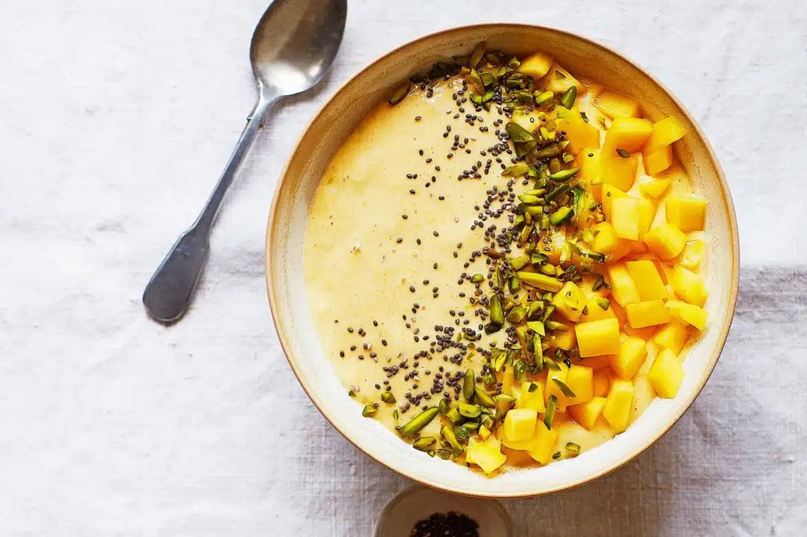 A mango smoothie bowl topped with diced mango pistachios and chia seeds